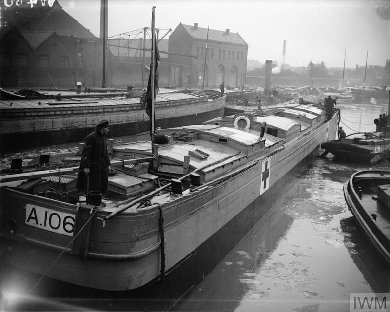A tug towing a hospital barge down a canal in north west France. © IWM (Q 33444)