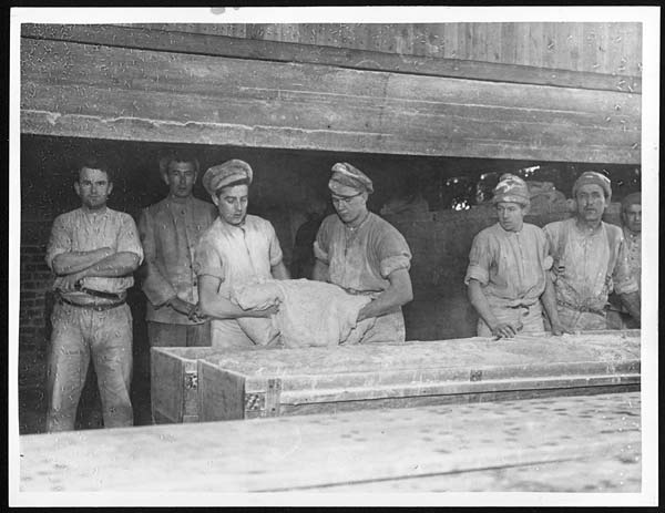 Taking the dough out of the bins to be made up into loaves.  Attribution National Library of Scotland License: CC BY 4.0