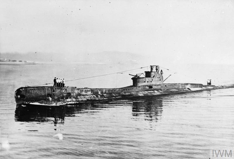 A Royal Navy submarine in open sea, crew standing on deck. © IWM (Q 67710)